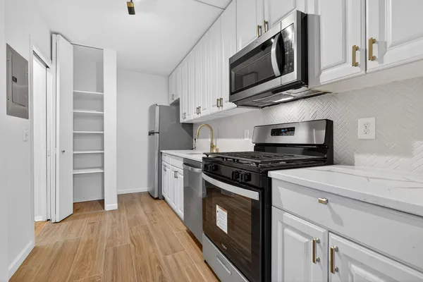 a kitchen with stainless steel appliances granite countertop a stove top oven a refrigerator a sink and dishwasher with wooden floor