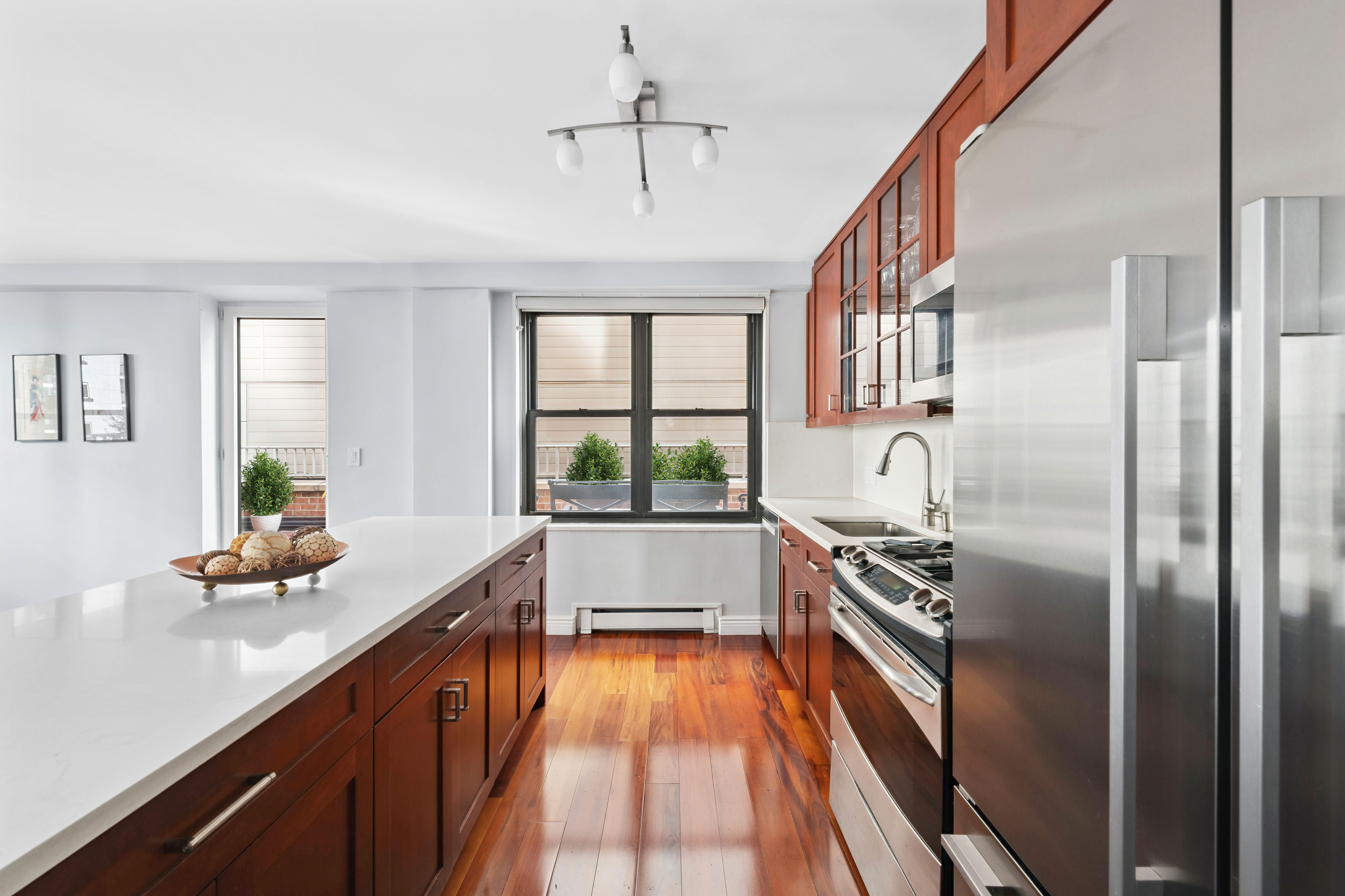 305 East 40th Street, Unit 19CD Manhattan, NY 10016 - Photo 4 of 16 a kitchen with stainless steel appliances granite countertop a refrigerator a sink dishwasher a stove and white countertops with wooden floor