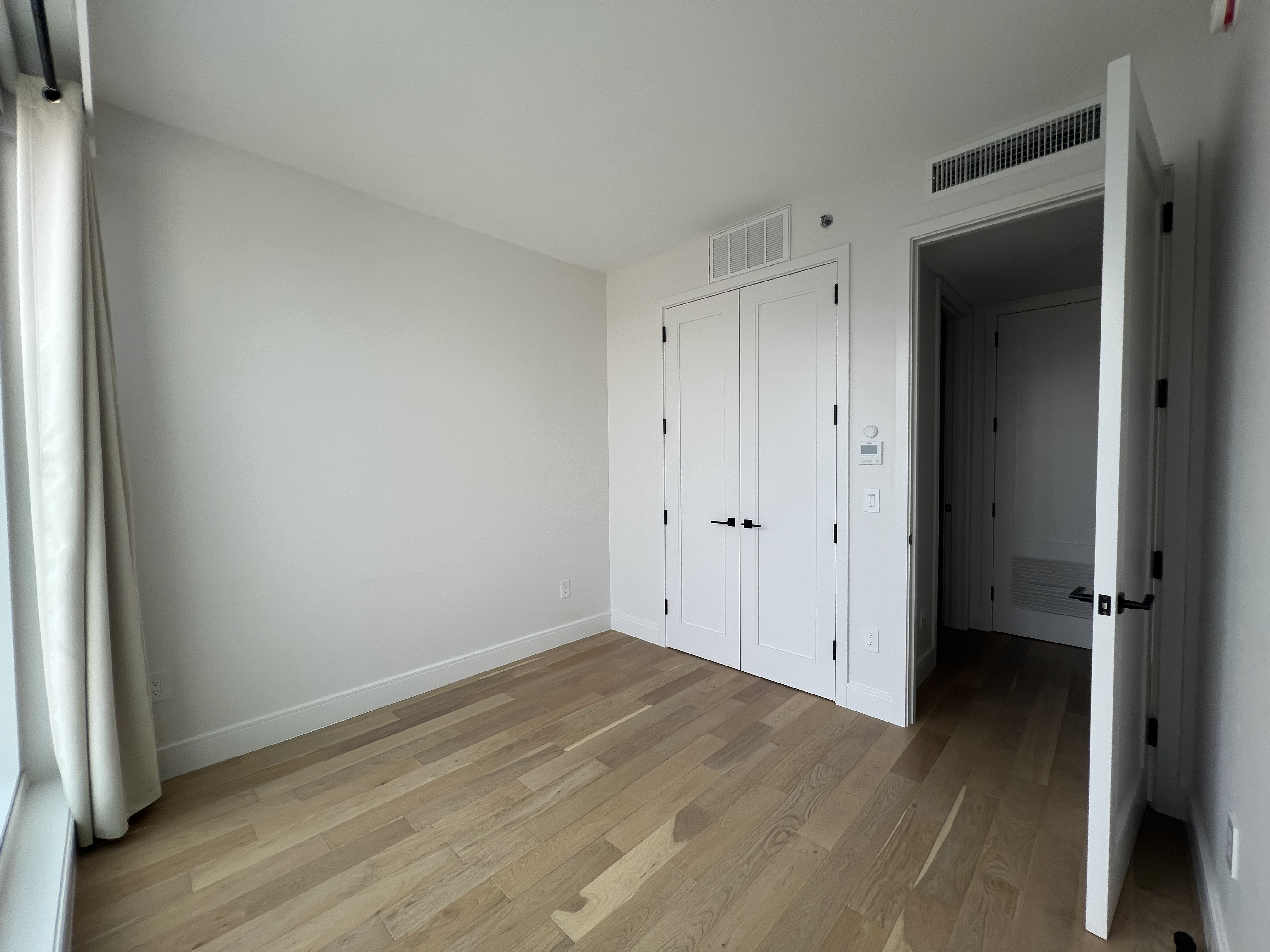 37-34 33rd Street, Unit 7H Queens, NY 11101 - Photo 12 of 18 an empty room with wooden floor and closet