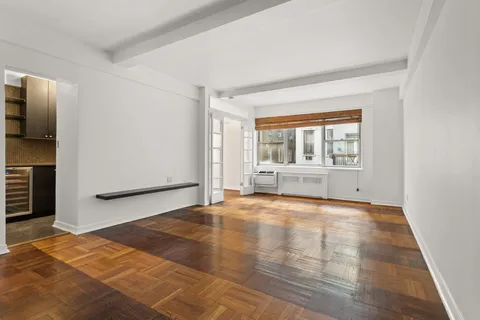 a view of an empty room with a window and wooden floor