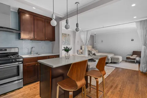 a kitchen with stainless steel appliances granite countertop a sink a stove a refrigerator and island with wooden floor