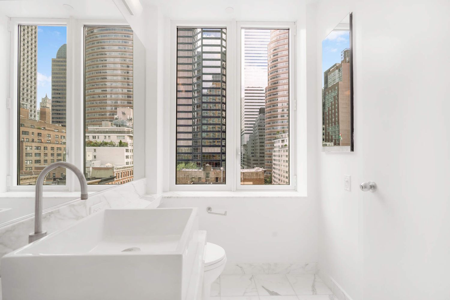 250 East 53rd Street, Unit 1001 Manhattan, NY 10022 - Photo 10 of 18 a bathroom with a sink a toilet and a window