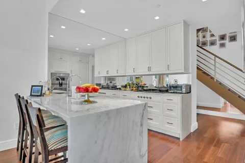 a kitchen with granite countertop a white table chairs and white cabinets