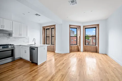 a kitchen with wooden floors and white cabinets