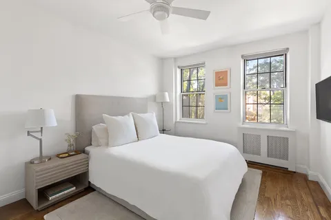 a bedroom with a bed a window and potted plant on the dresser