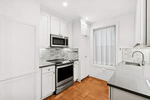 a kitchen with granite countertop a sink stove and microwave