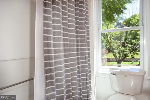 a bathroom with a sink a toilet a window and a shower