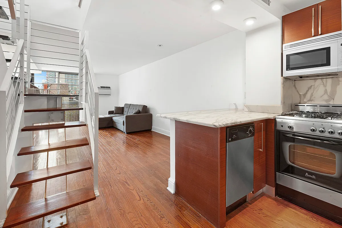 184 Thompson Street, Unit 6D Manhattan, NY 10012 - Photo 3 of 7 a kitchen with stainless steel appliances granite countertop a stove and a microwave