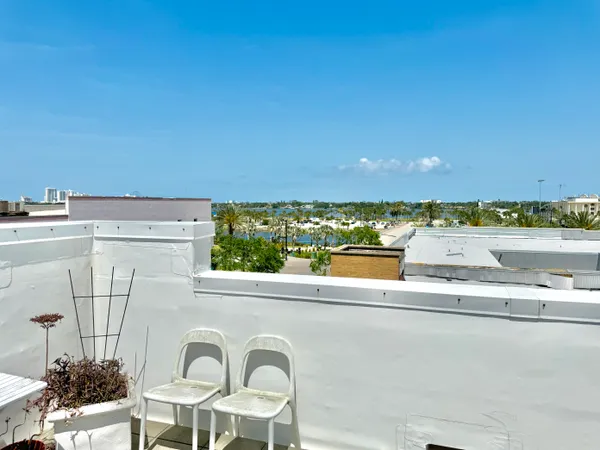 a living room with patio furniture and a dining table with kitchen view