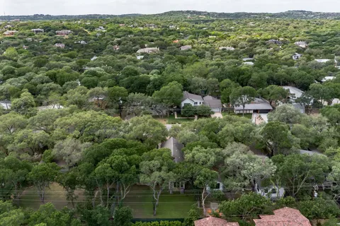 an aerial view of residential houses with outdoor space and trees