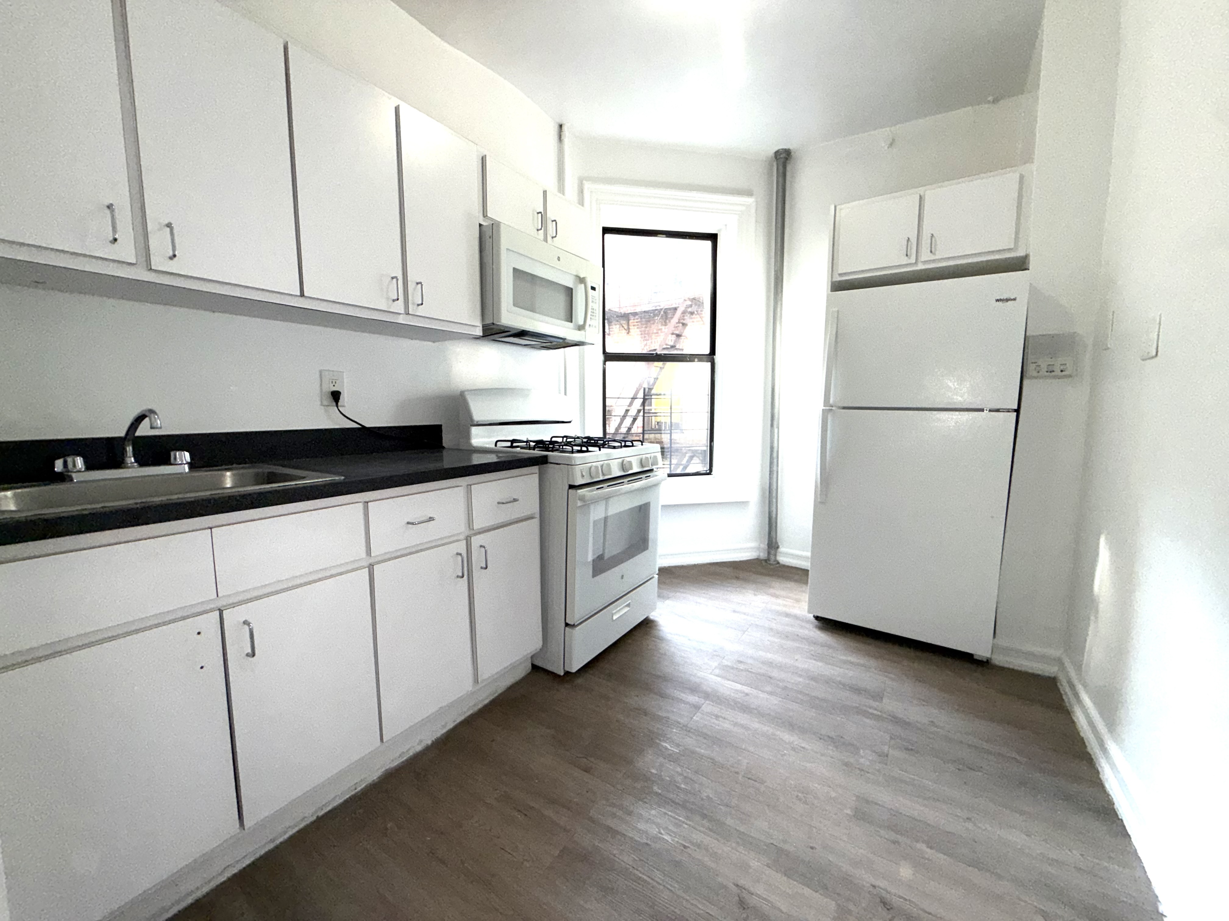 153 Vermilyea Avenue, Unit 4B Manhattan, NY 10034 - Photo 7 of 9 a kitchen with stainless steel appliances granite countertop a refrigerator sink and cabinets