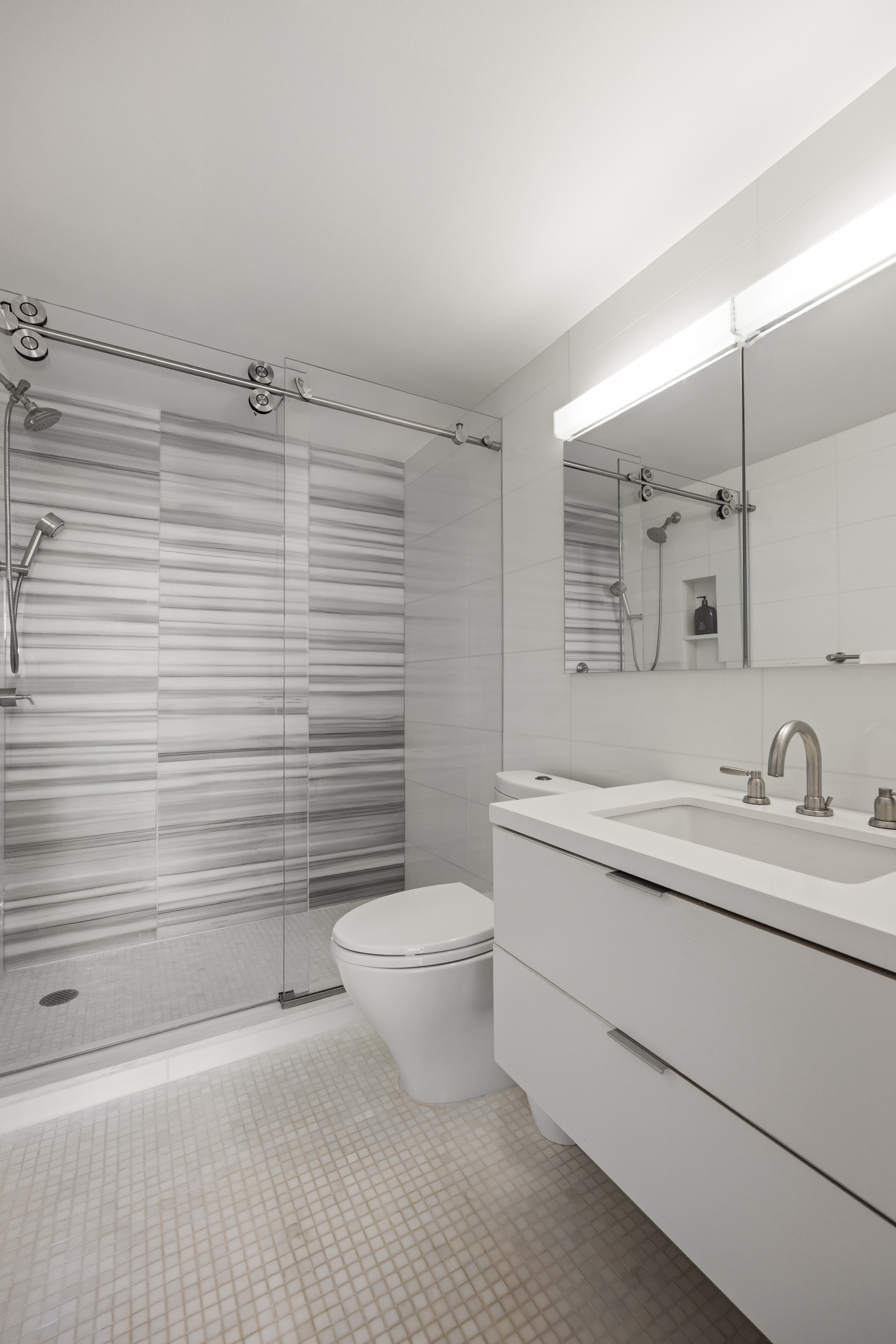 860 United Nations Plaza, Unit 16G Manhattan, NY 10017 - Photo 11 of 12 a bathroom with a granite countertop toilet a sink and a mirror