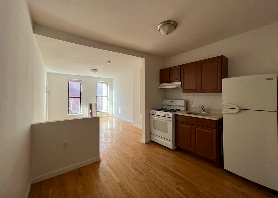 446 West 46th Street, Unit 16 Manhattan, NY 10036 - Photo 3 of 12 a kitchen with stainless steel appliances granite countertop a refrigerator stove top oven and cabinets with wooden floor