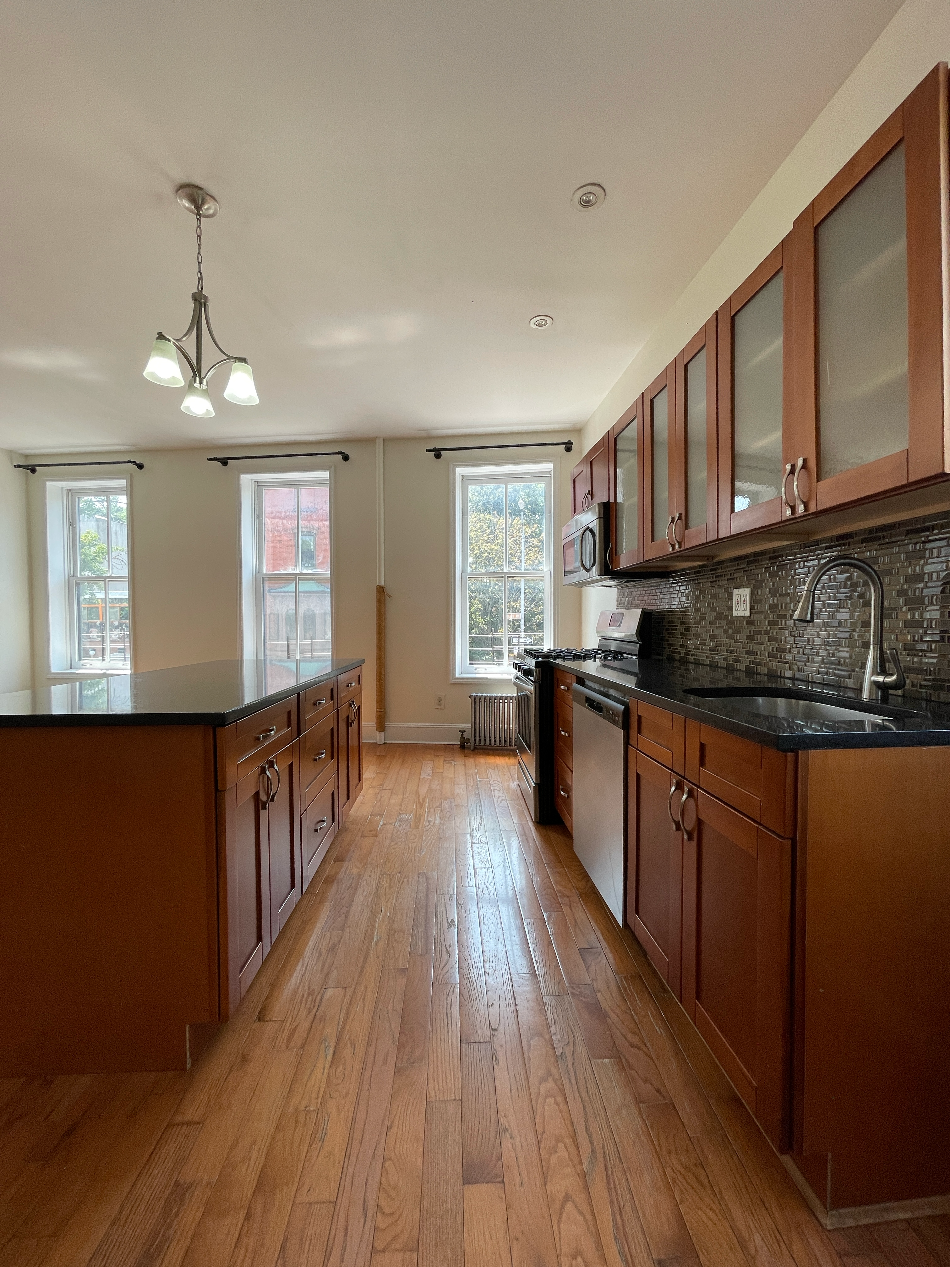 a kitchen with stainless steel appliances granite countertop a stove a sink dishwasher a refrigerator and wooden floor