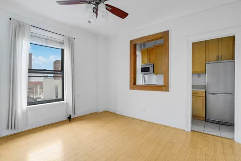 a view of an empty room with window and refrigerator
