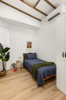 a bedroom with a bed and a potted plant on the dresser