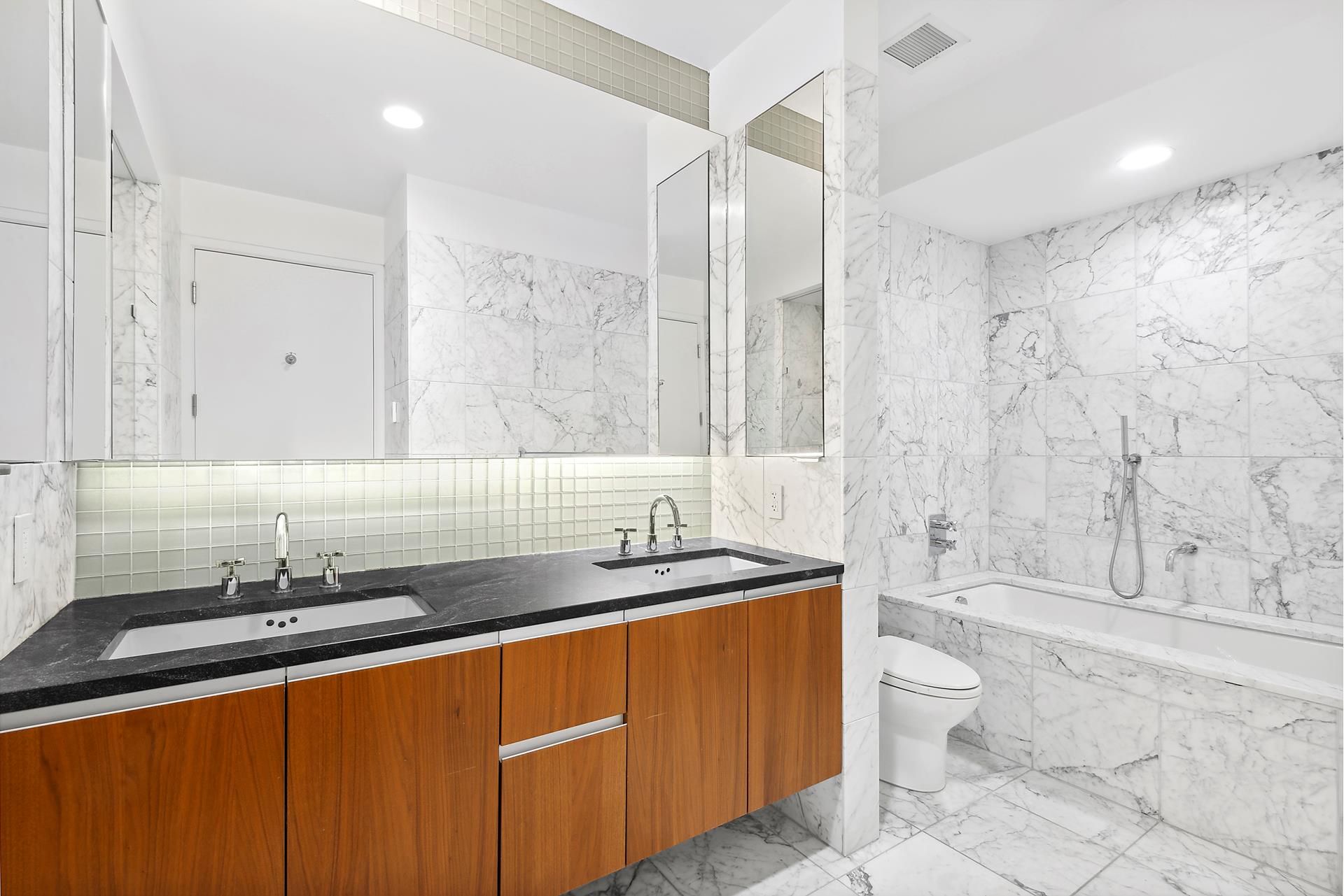 311 West Broadway, Unit 5G Manhattan, NY 10013 - Photo 6 of 14 a bathroom with a granite countertop sink a toilet a mirror and bathtub
