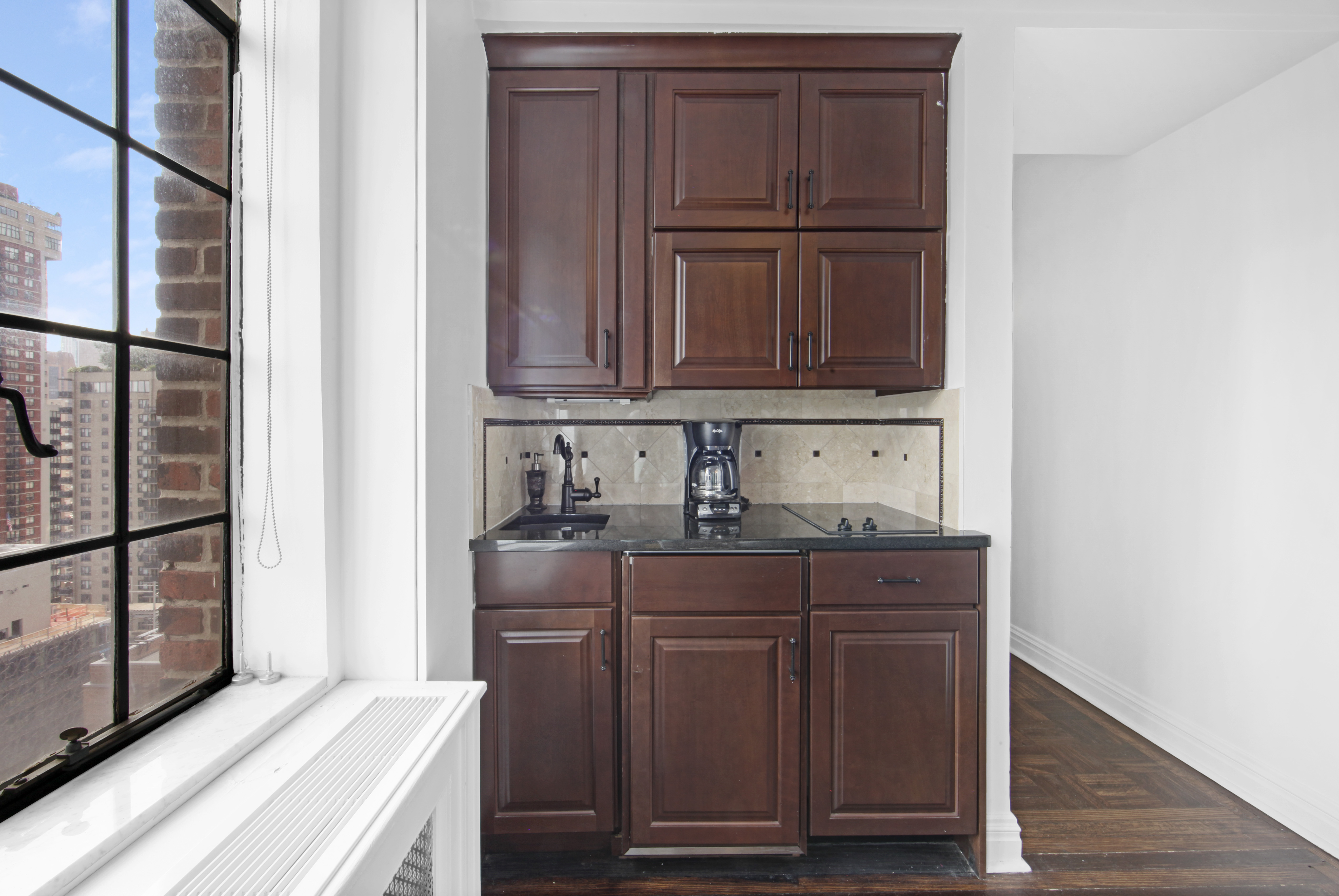 320 East 42nd Street, Unit 3012 Manhattan, NY 10017 - Photo 6 of 12 a kitchen with granite countertop wooden cabinets and sink