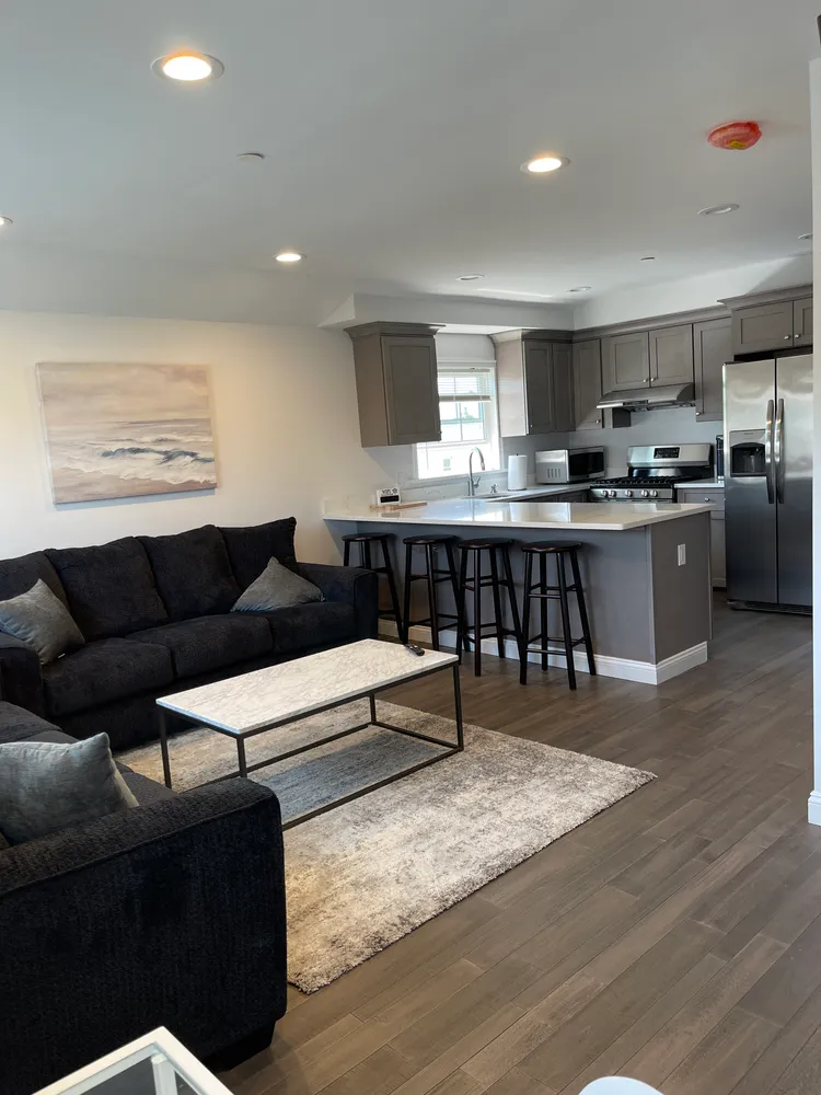 a living room with stainless steel appliances furniture and kitchen view