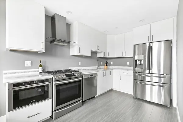 a kitchen with cabinets stainless steel appliances and wooden floor