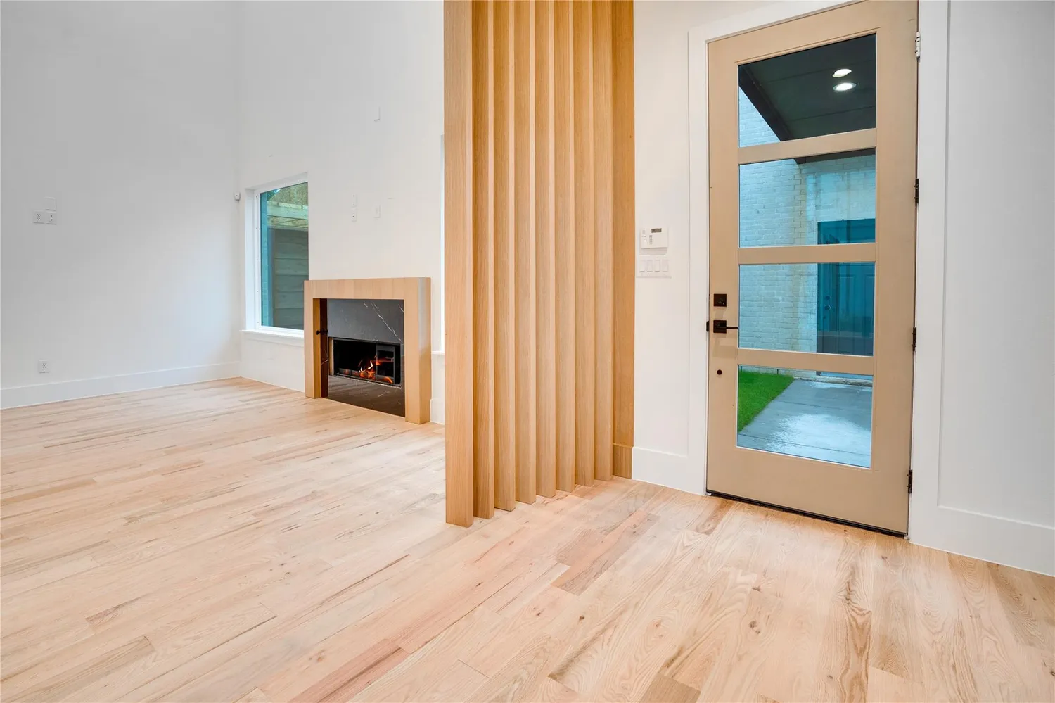 an empty room with wooden floor fireplace and windows