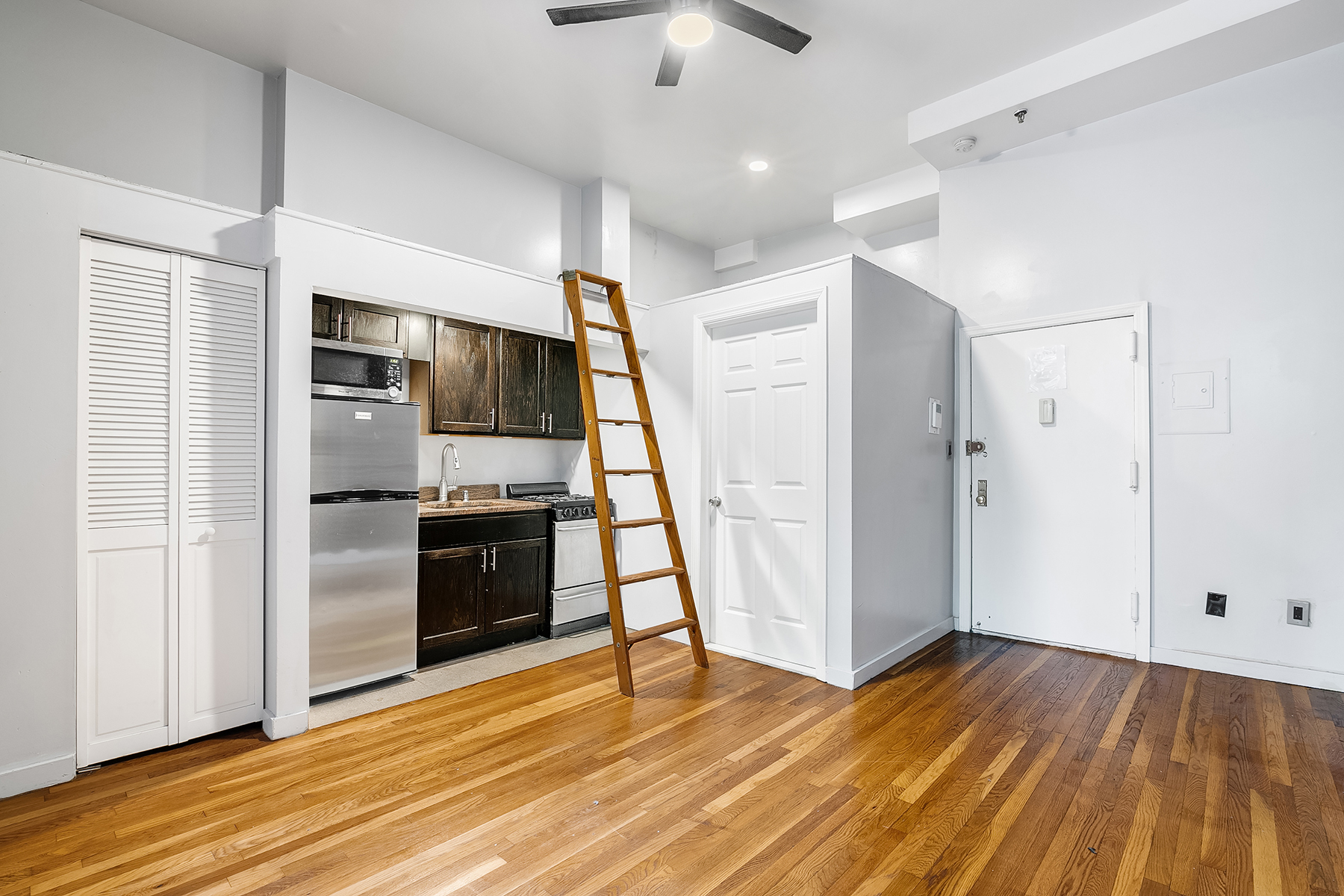 357 West 120th Street, Unit 1R Manhattan, NY 10027 - Photo 3 of 9 a view of a kitchen with wooden floor electronic appliances and stairs