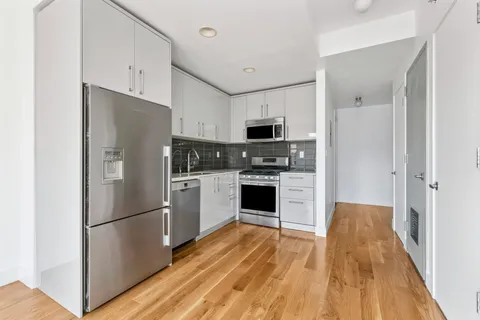 a kitchen with cabinets stainless steel appliances and wooden floor