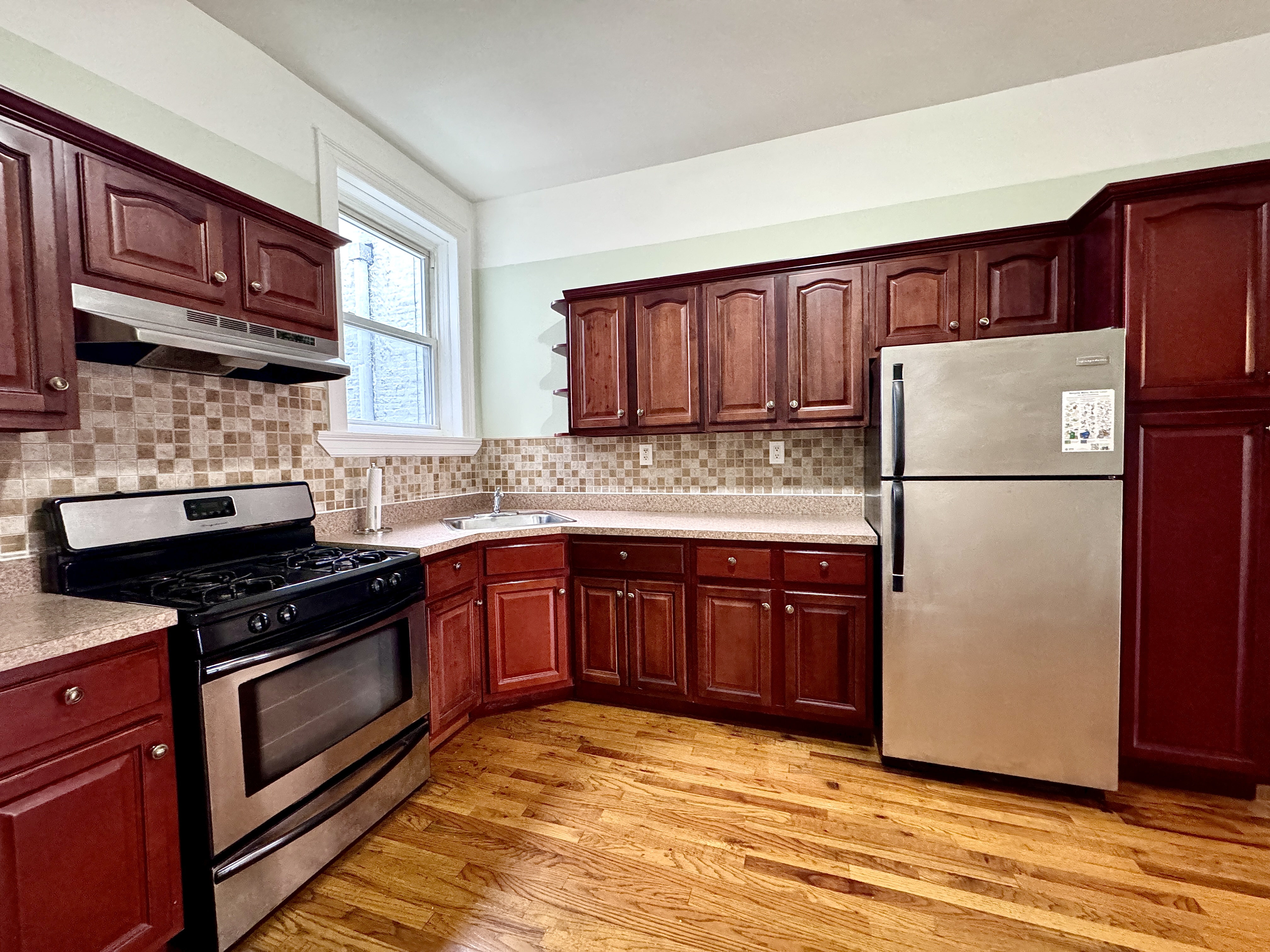 497 Park Place, Unit 4 Brooklyn, NY 11238 - Photo 10 of 14 a kitchen with a refrigerator stove and wooden cabinets