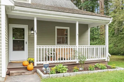 a front view of a house with two chairs and a potted plant