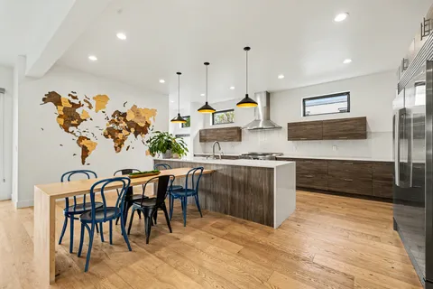 a kitchen with stainless steel appliances kitchen island granite countertop a stove a sink a dining table and chairs