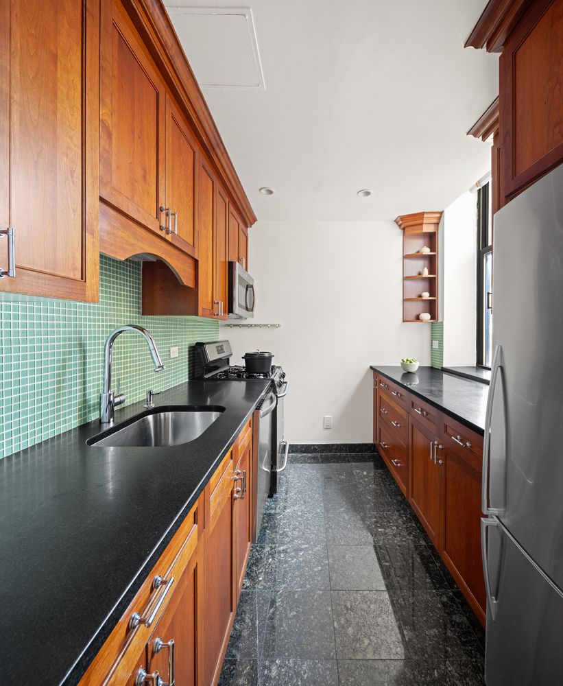 1255 5th Avenue, Unit 6D Manhattan, NY 10029 - Photo 6 of 15 a kitchen with stainless steel appliances granite countertop a sink and a refrigerator