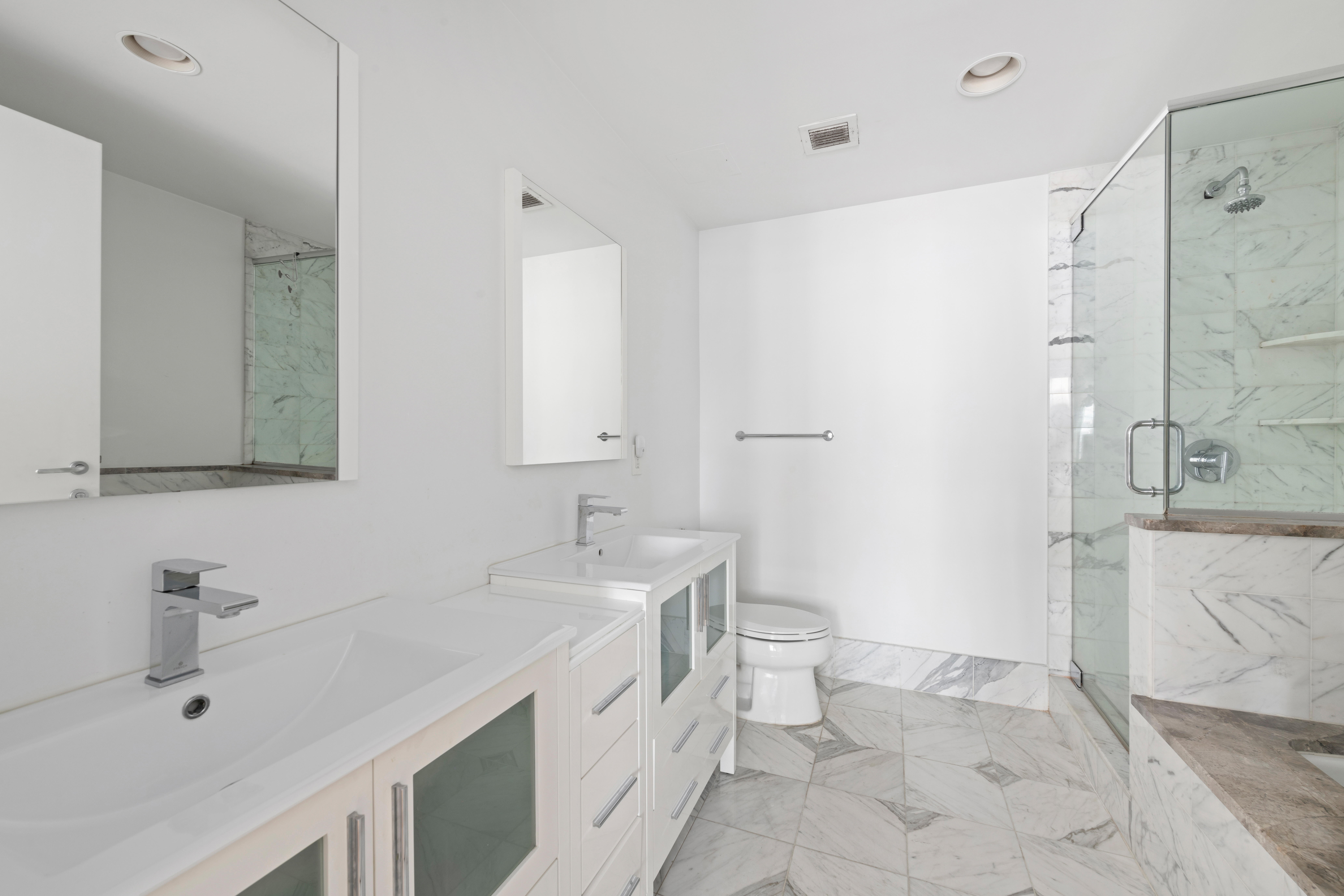 446 Kent Avenue, Unit 14A Brooklyn, NY 11249 - Photo 12 of 19 a spacious bathroom with a double vanity sink toilet mirror and shower
