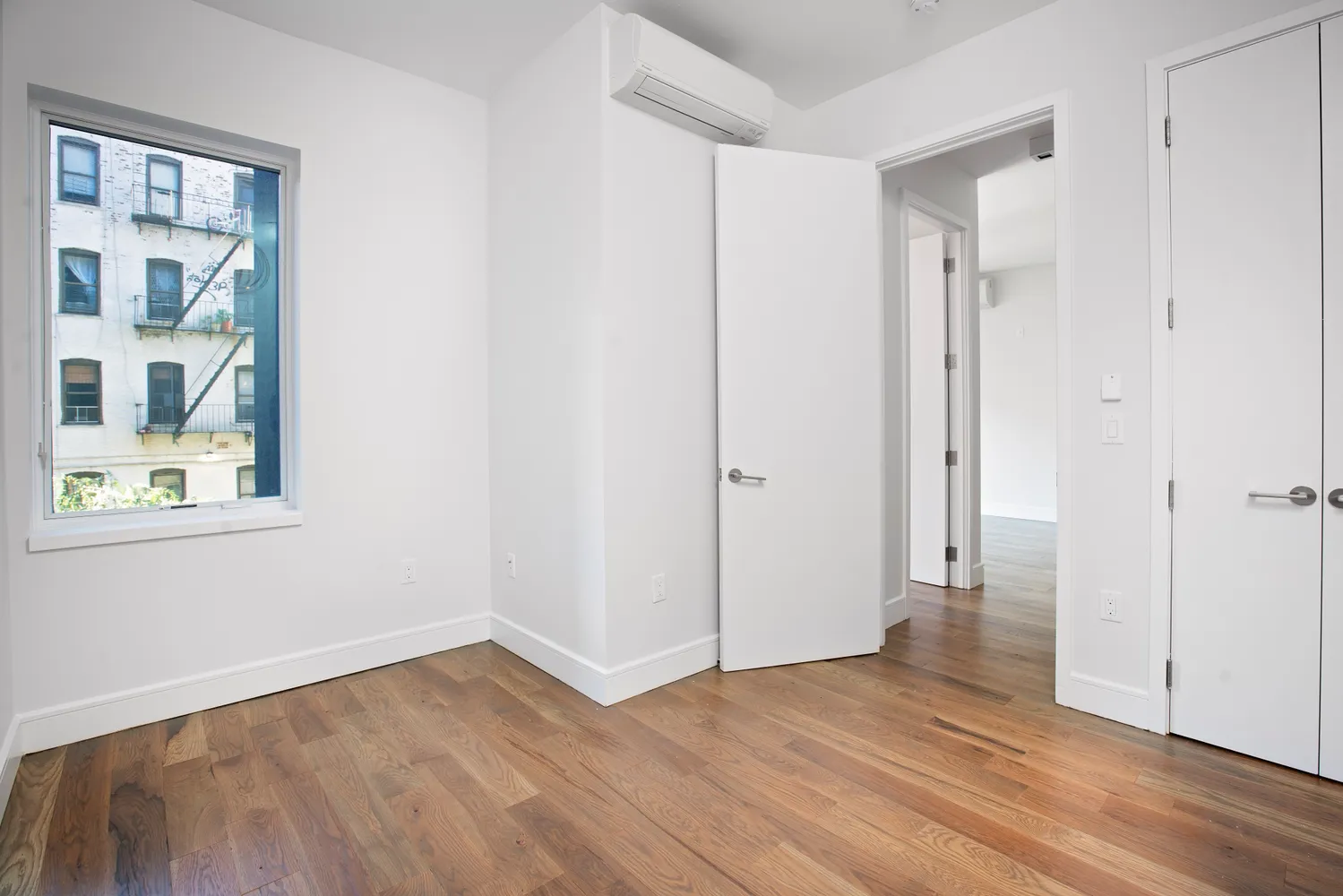a view of an empty room with wooden floor and a window