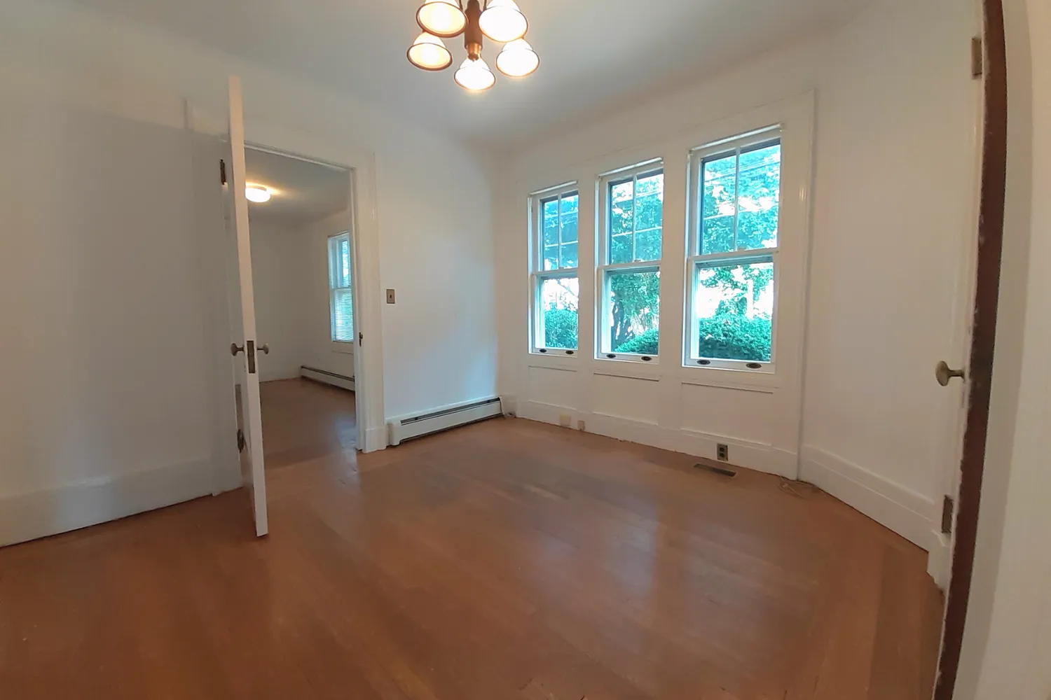 an empty room with wooden floor and window