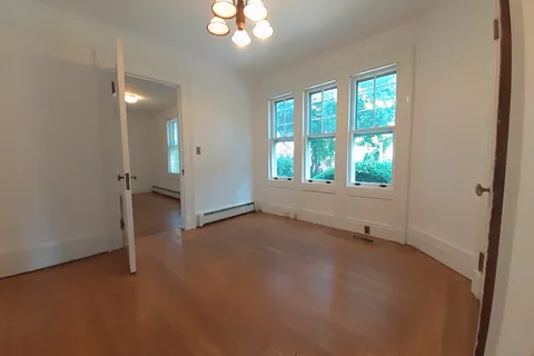 an empty room with wooden floor and window