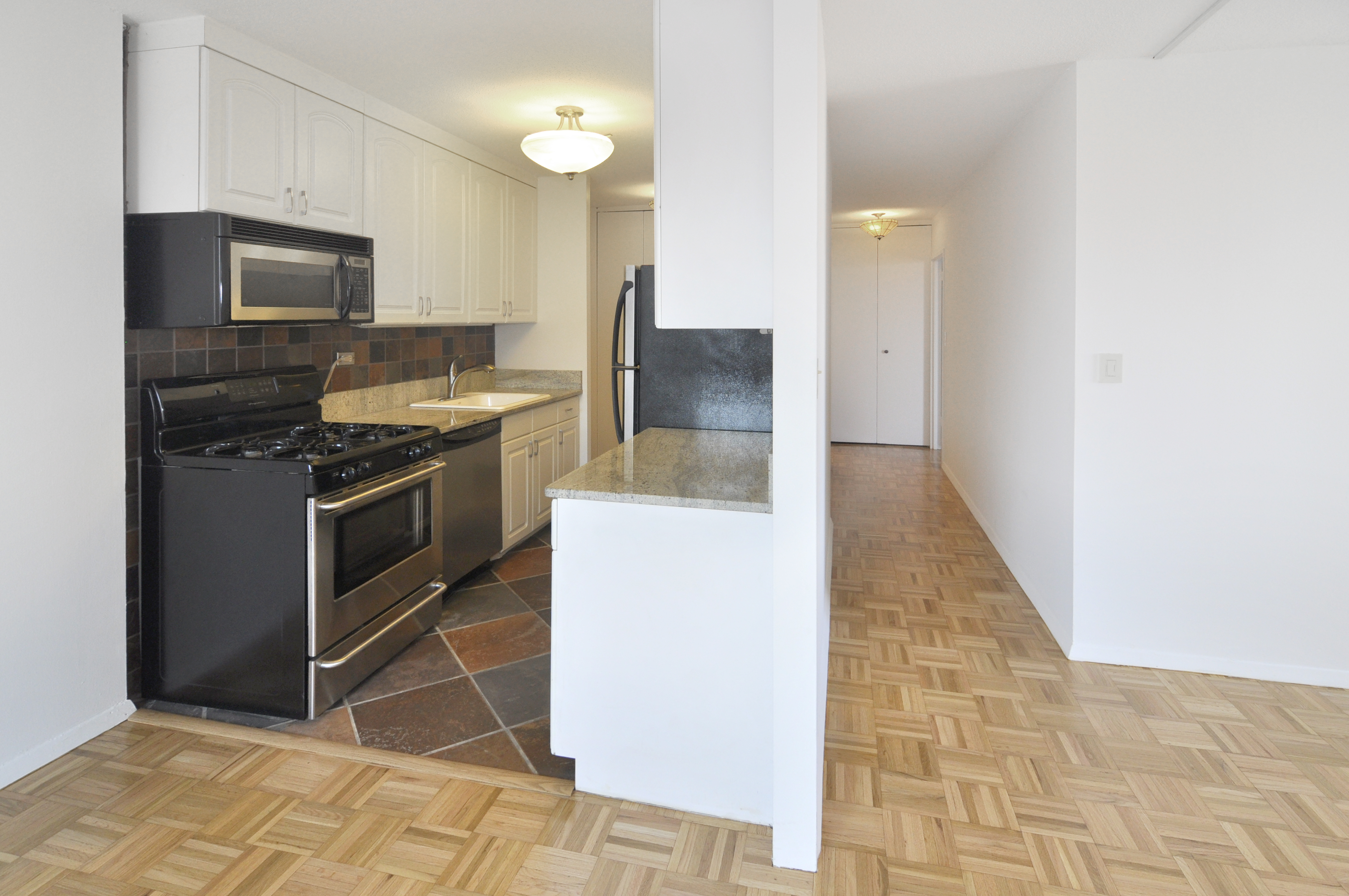 1623 3rd Avenue, Unit 25C Manhattan, NY 10128 - Photo 2 of 12 a kitchen with granite countertop a stove top oven and cabinets