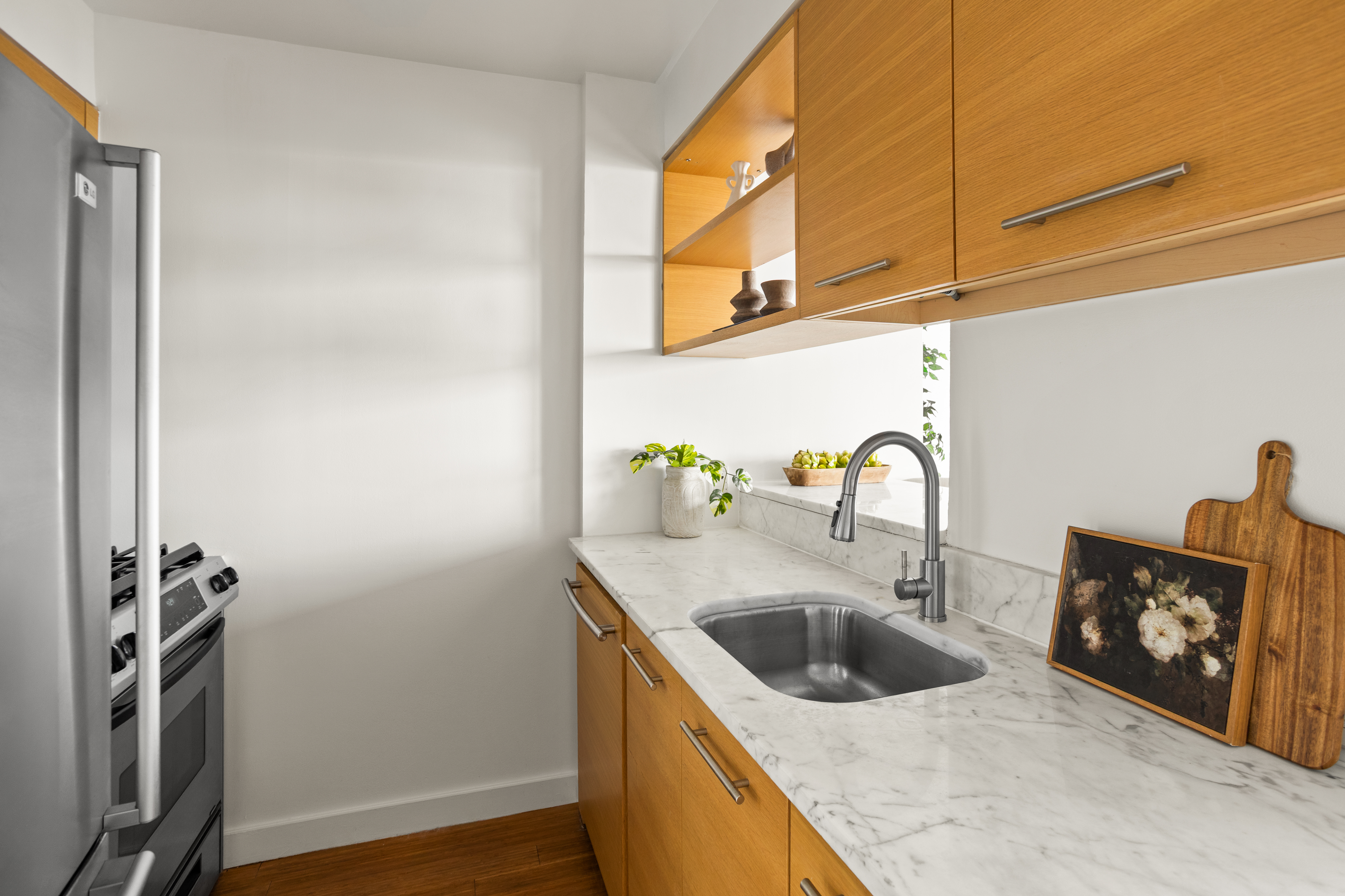 100 West 39th Street, Unit 38I Manhattan, NY 10018 - Photo 7 of 10 a kitchen with stainless steel appliances granite countertop a sink a stove and a refrigerator