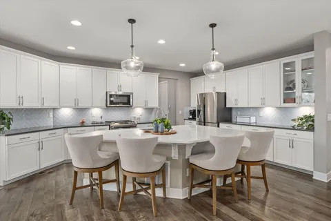 a kitchen with stainless steel appliances granite countertop a dining table chairs stove microwave and cabinets