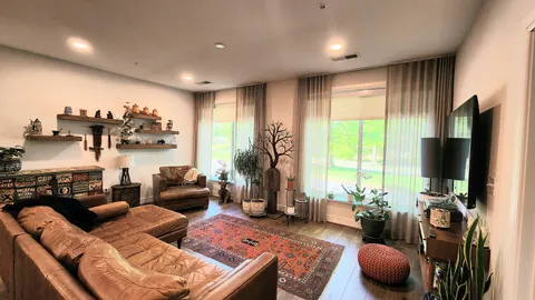 a living room with furniture a flat screen tv and a large window