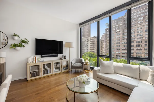 a living room with furniture a flat screen tv and a large window