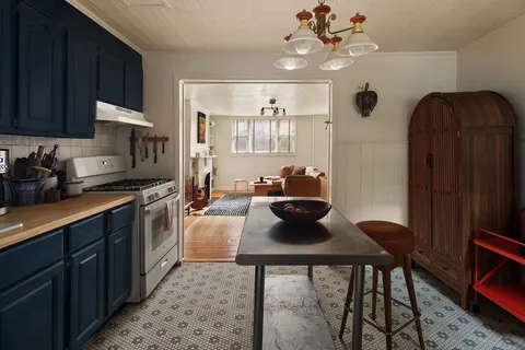 a kitchen with stainless steel appliances granite countertop a stove a refrigerator a sink a dining table and chairs with wooden floor