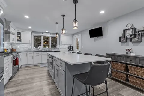 a kitchen with kitchen island a sink and a stove with wooden floor