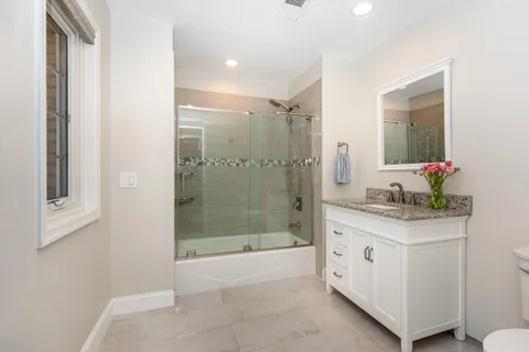a bathroom with a granite countertop sink a mirror and a shower