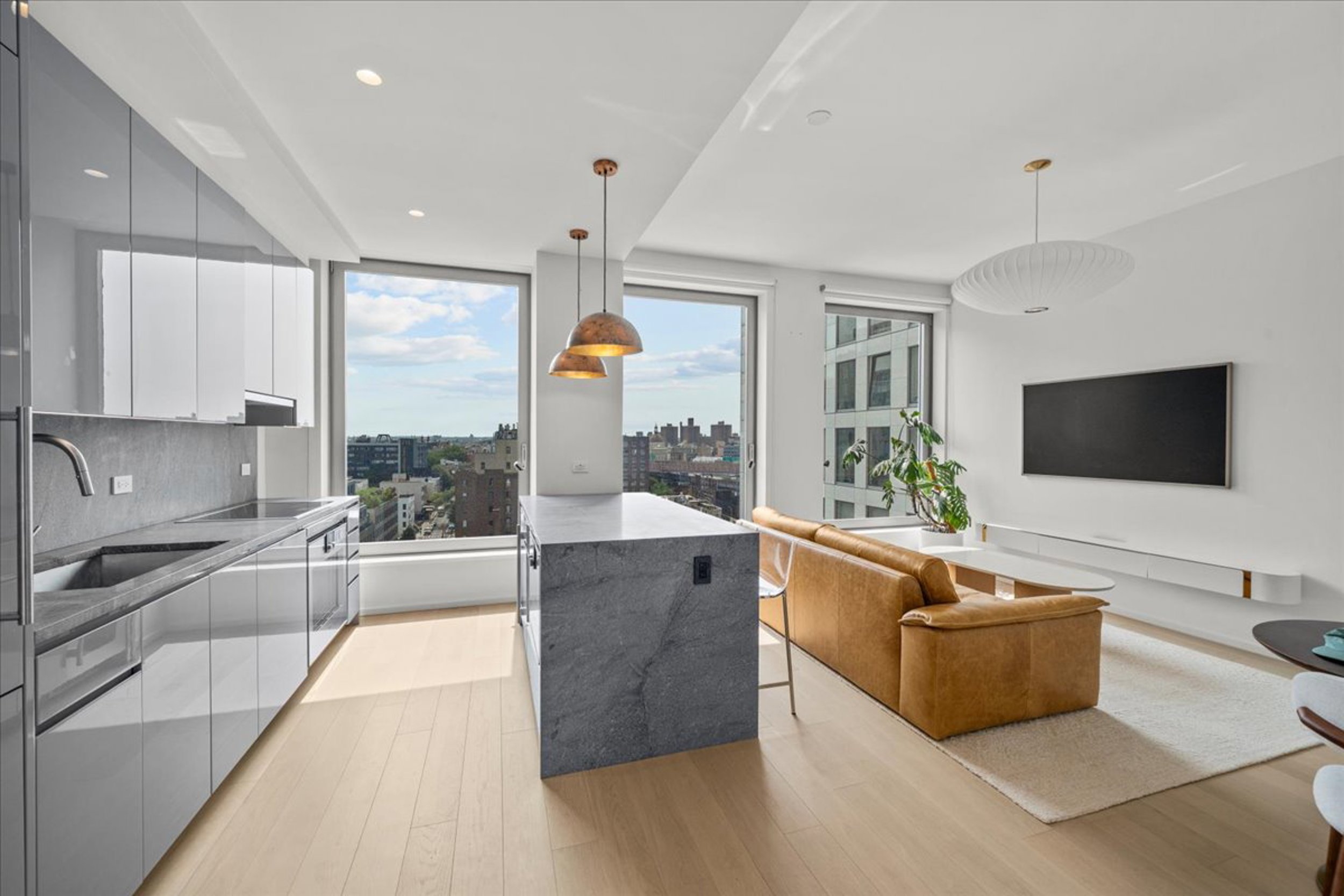 8 South 4th Street, Unit 15D Brooklyn, NY 11249 - Photo 3 of 29 a large living room with stainless steel appliances granite countertop a couch a flat screen tv and a large window