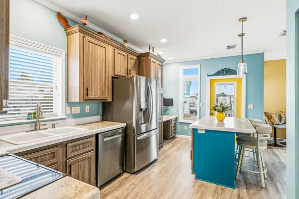 a kitchen with stainless steel appliances granite countertop a refrigerator a sink a stove and a center island with wooden floor