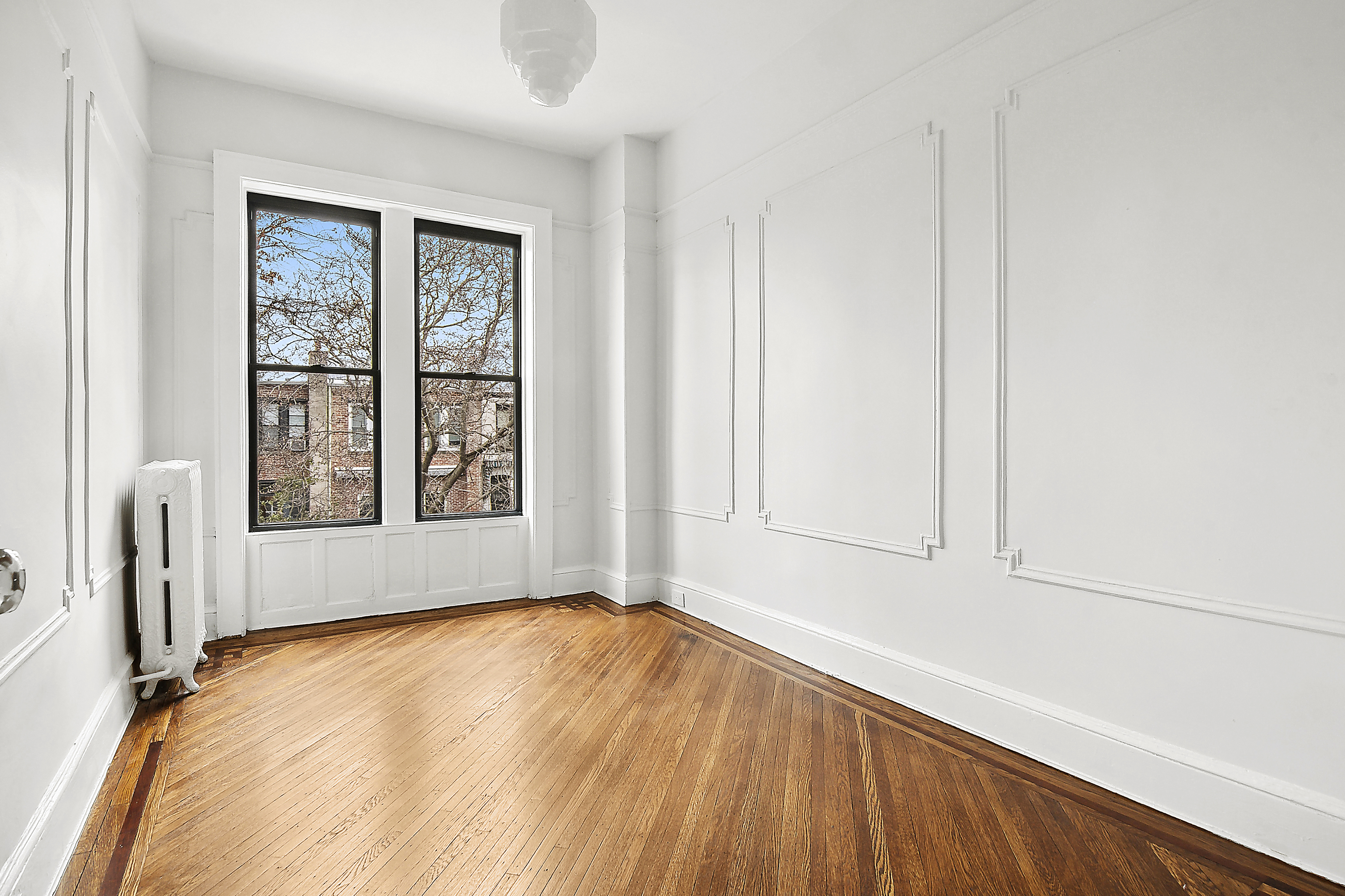 195 Rutland Road Brooklyn, NY 11225 - Photo 13 of 21 a view of an empty room with a window and wooden floor