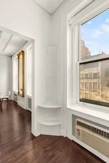 a view of an empty room with a window and wooden floor