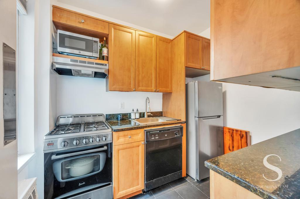 7 Lexington Avenue, Unit 5E Manhattan, NY 10010 - Photo 12 of 27 a kitchen with stainless steel appliances granite countertop a stove a sink and a microwave