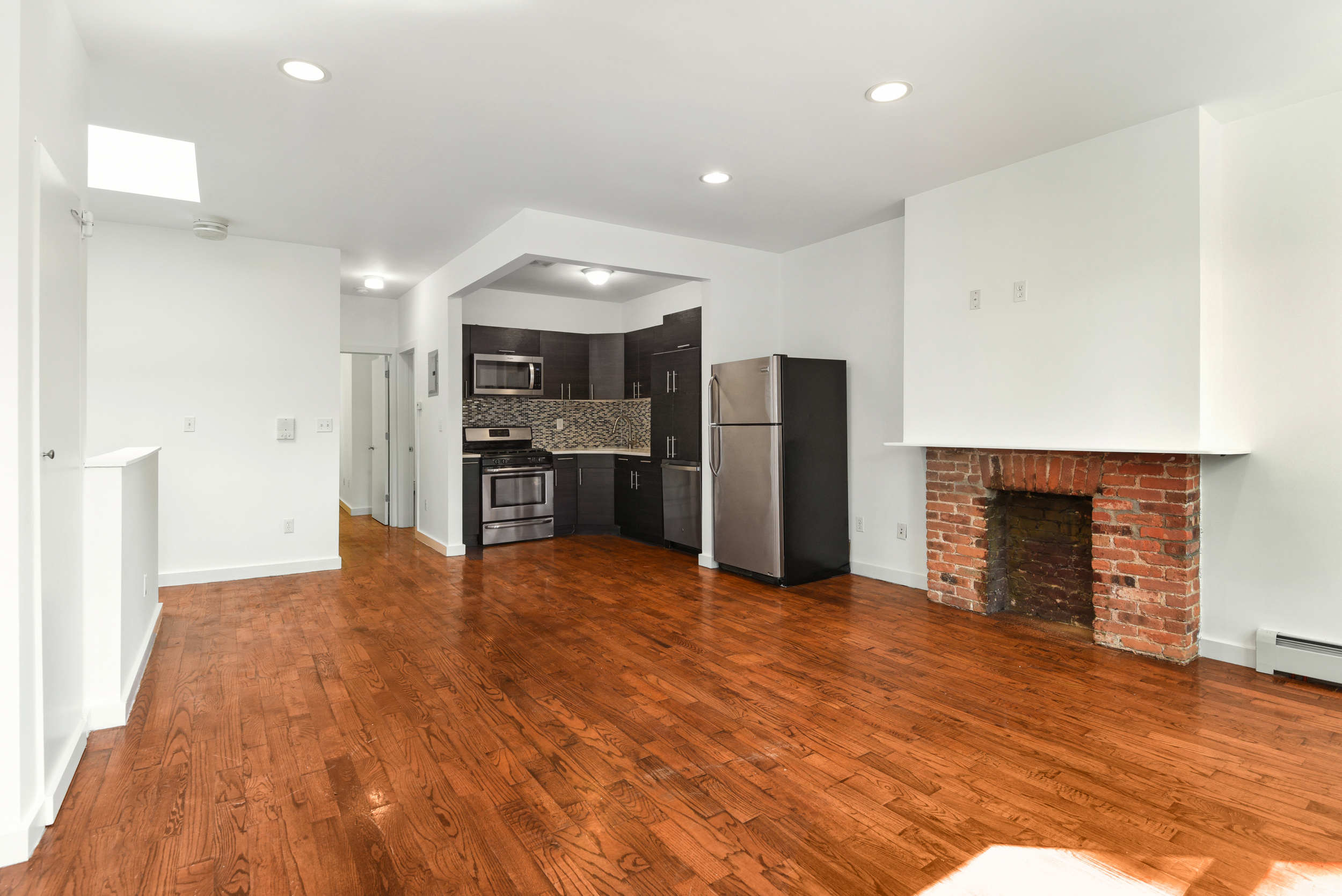 1076 Decatur Street, Unit 2 Brooklyn, NY 11207 - Photo 3 of 11 an empty room with kitchen and fireplace