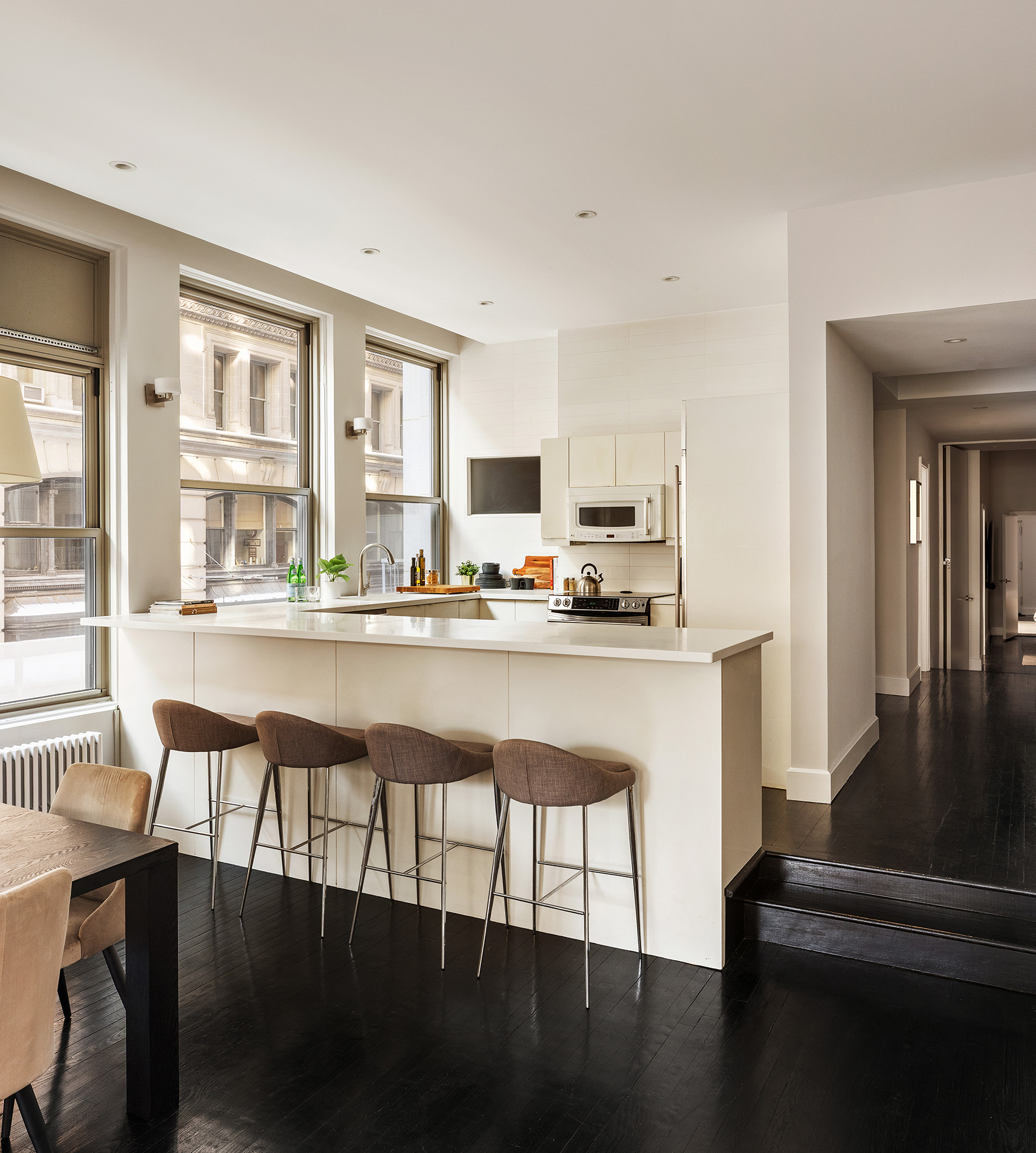 142 5th Avenue, Unit 2 Manhattan, NY 10011 - Photo 6 of 18 a kitchen with stainless steel appliances granite countertop a stove top oven a dining table and chairs with wooden floor